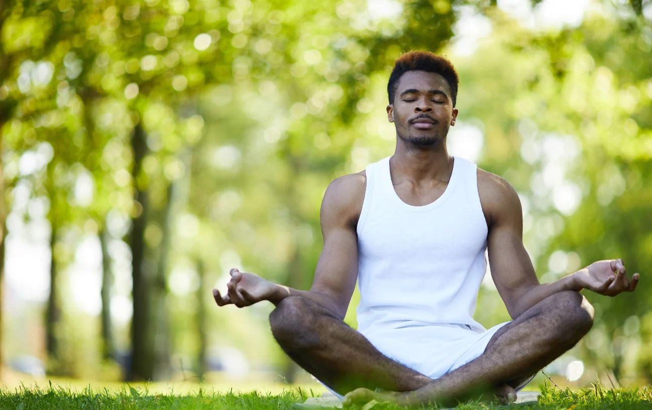 a person of color meditating in the woods.